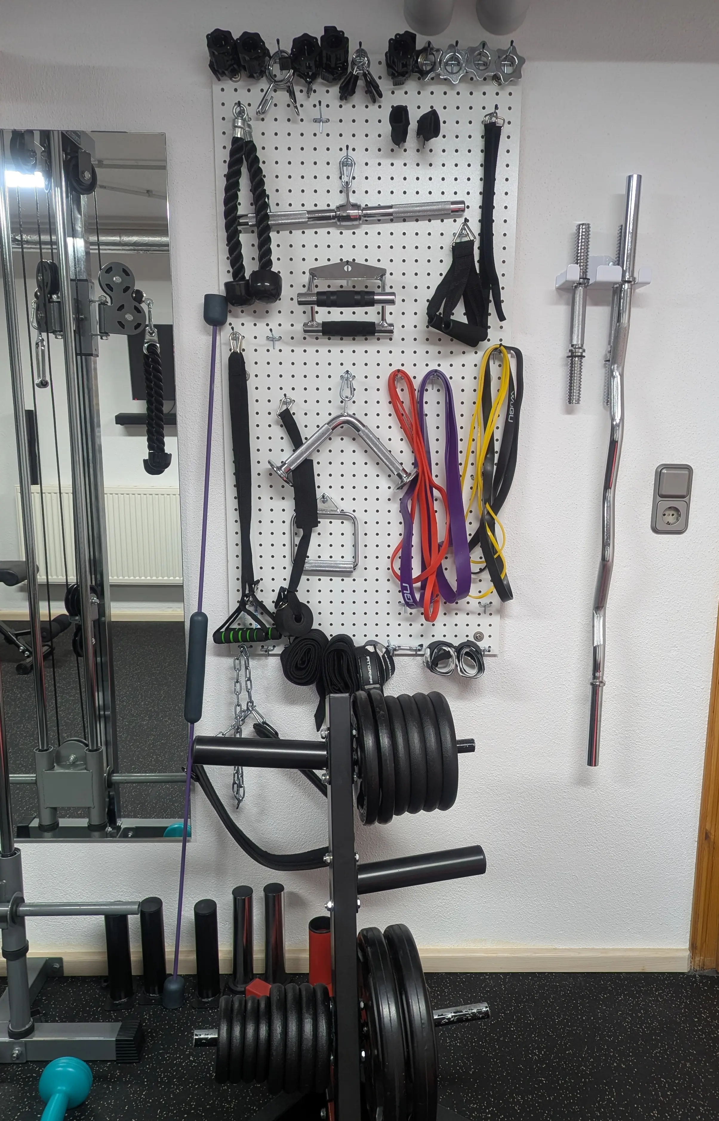 Platzsparende Aufbewahrung – alles griffbereit Organisierte Zubehörwand mit Kabelaufsätzen, Widerstandsbändern und Gewichtsscheiben