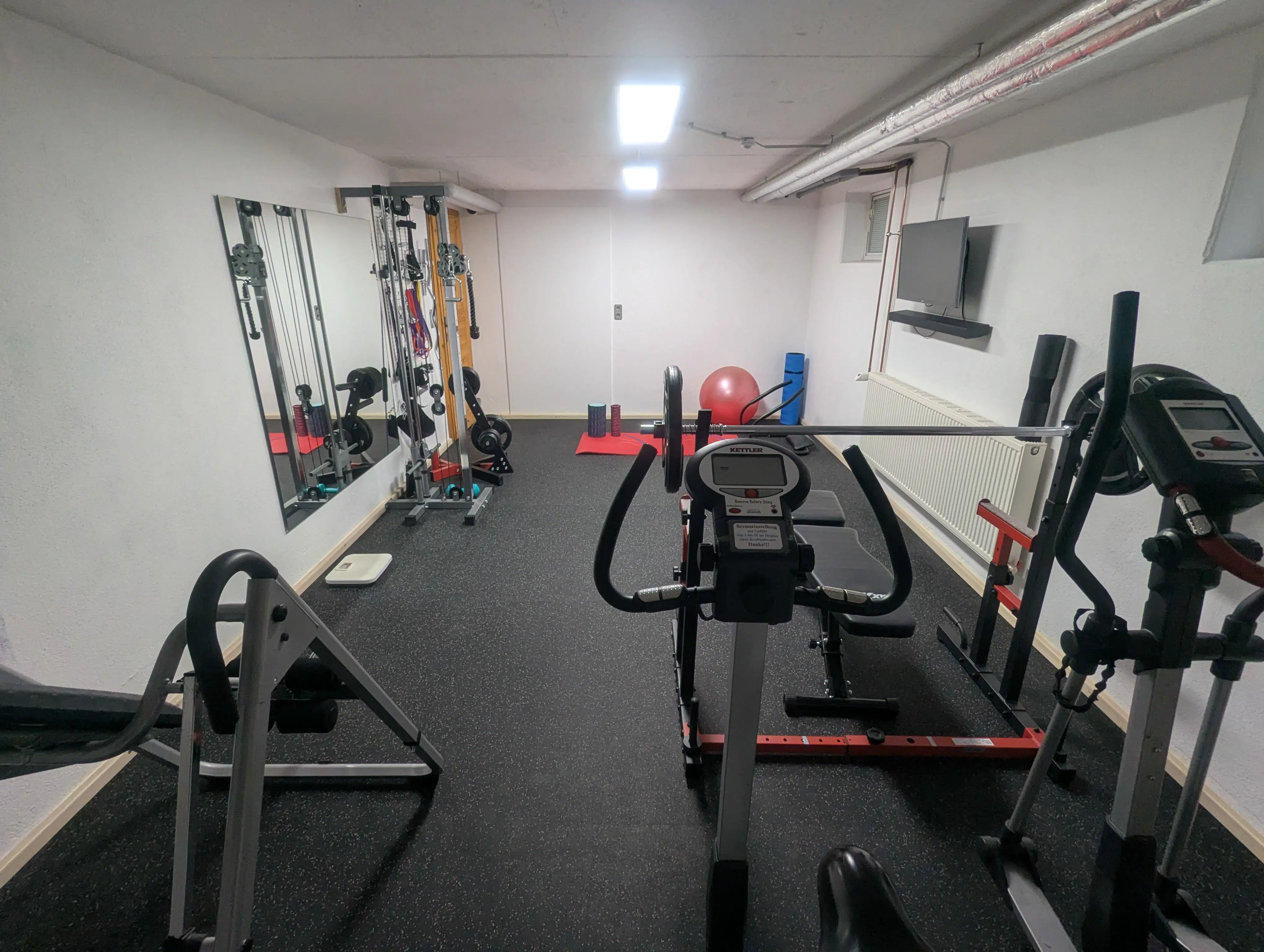 Gesamtansicht des Fitnessraums am Birkholmhof mit Cardiogeräten und Kraftstation